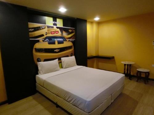 a bedroom with a bed and a poster of a car at NewYork Suite Hotel in Ban Ko