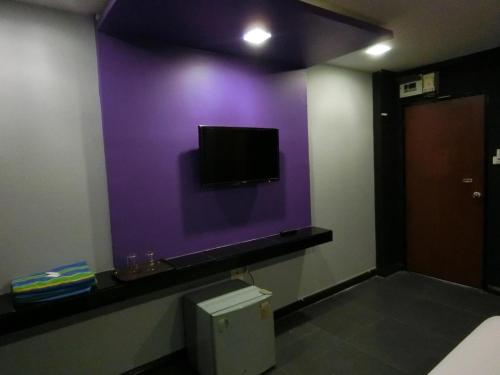 a room with a purple wall with a toilet and a tv at NewYork Suite Hotel in Ban Ko