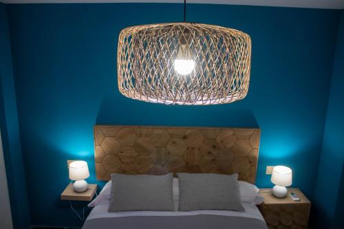 a bedroom with a blue wall with a bed and a pendant light at Ático con terraza en Cuesta Gomérez in Granada