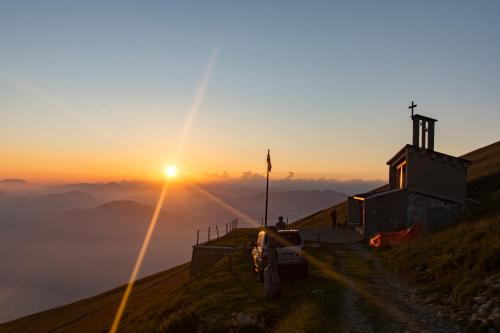 a church on top of a hill with the sun setting at Rifugio Chierego - 1911m in Brenzone sul Garda
