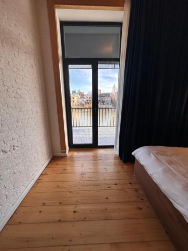 a bedroom with a large window and a wooden floor at Apartment Riverside in Kutaisi