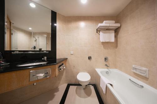a bathroom with a tub and a toilet and a sink at Furama City Centre in Singapore