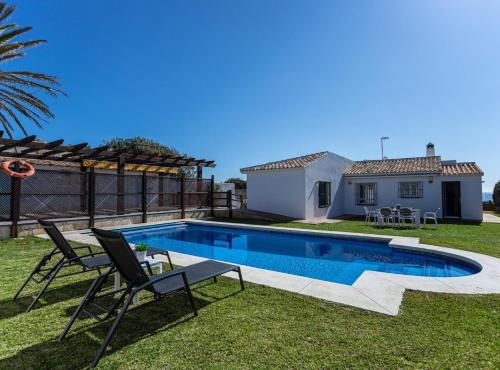 - une piscine avec 2 chaises et une maison dans l'établissement Charming villa on the seafront, à Marbella