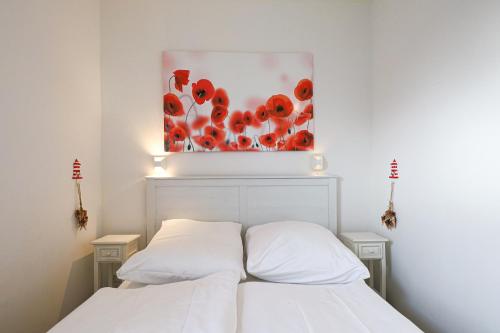 - une chambre avec un lit blanc orné d'une peinture murale dans l'établissement Appartement Seesternchen, à Wenningstedt