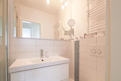 La salle de bains blanche est pourvue d'un lavabo et d'un miroir. dans l'établissement Appartement Seesternchen, à Wenningstedt