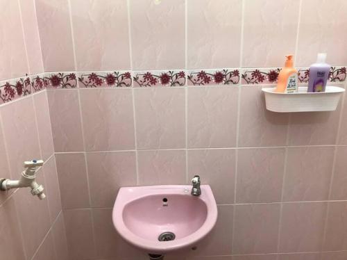 a bathroom with a pink sink on a tiled wall at Homestay Che Mat in Kuala Terengganu