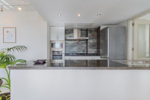 una cucina con armadi bianchi e ripiani in granito di Playamar a Torremolinos