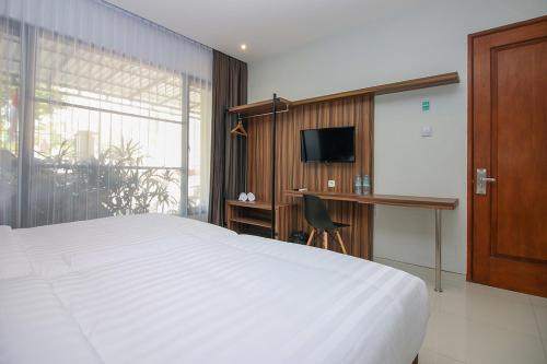 a bedroom with a bed and a desk and a television at TwoSpaces Living at Kencana Residence in Gunungsan