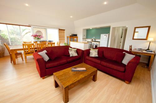 a living room with two red couches and a table at Ocean Mist Villa in Albany