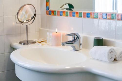 a bathroom with a sink and a mirror and a candle at Il Casale delle Rose in Paganico