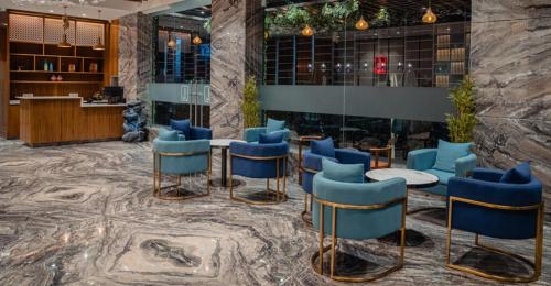a lobby with blue chairs and tables and a counter at Lords Inn Rajkot in Rajkot