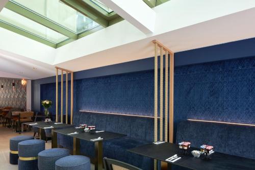 a dining room with blue walls and tables and chairs at Hôtel Tourisme Avenue in Paris