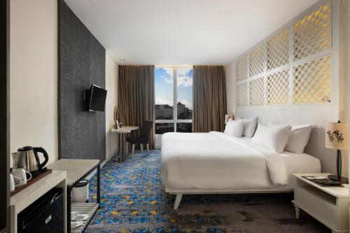 a hotel room with a large white bed and a window at Jambuluwuk Malioboro Hotel Yogyakarta in Yogyakarta