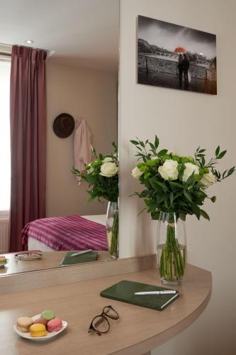 a desk with a table with flowers in a room at Hôtel Tourisme Avenue in Paris