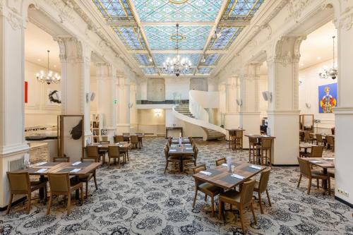 a dining room with tables and chairs and a ceiling at Nemzeti Hotel Budapest - MGallery Collection in Budapest