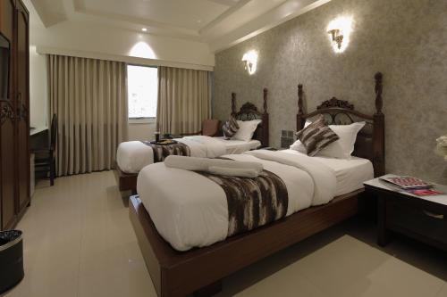 a hotel room with three beds with white sheets at Hotel Ariana Residency in Mumbai