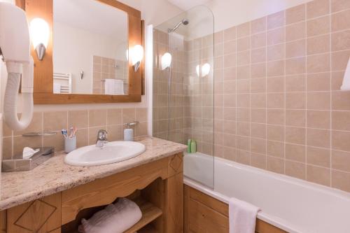 a bathroom with a sink and a tub and a mirror at Résidence Pierre & Vacances Premium Arc 1950 Le Village in Arc 1950