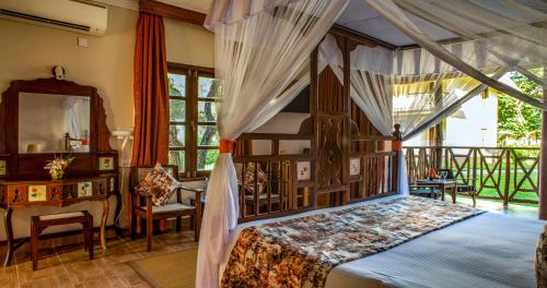 een slaapkamer met een hemelbed en een bureau bij Neptune Palm Beach Boutique Resort & Spa - All Inclusive in Galu