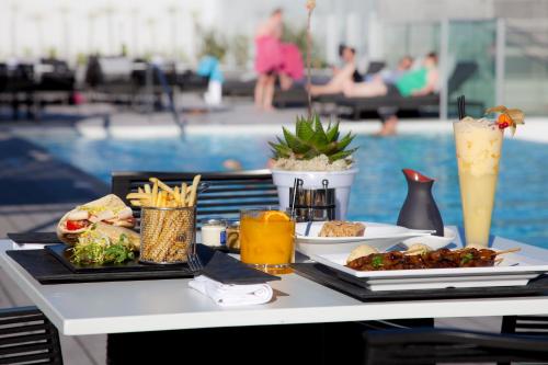 a table with food and drinks next to a pool at EPIC SANA Lisboa Hotel in Lisbon
