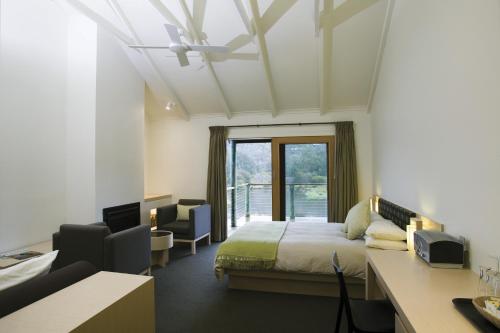 a bedroom with a bed and a desk and a window at Peppers Cradle Mountain Lodge in Cradle Mountain