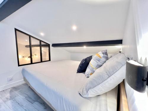 1 dormitorio con cama blanca y ventana en Le Loft ~ à 4 min de la gare, Fibre + Parking privé, en Poitiers