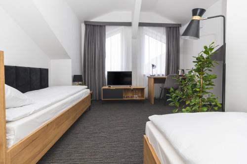 ein Hotelzimmer mit 2 Betten und einem TV in der Unterkunft Hotel Akwawit in Leszno