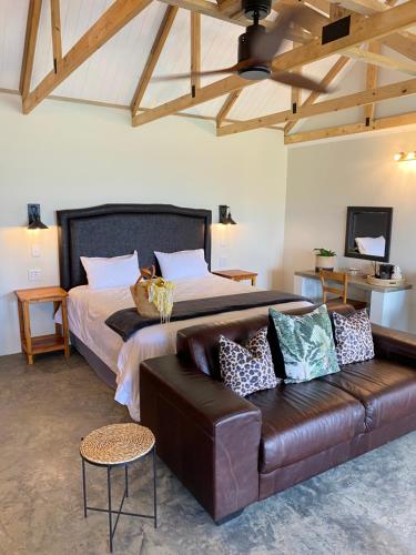 a bedroom with a bed and a leather couch at Berghouse and Cottages in Langkloof