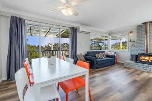 uma sala de estar com uma mesa e cadeiras brancas e uma lareira em Sunflower Cottage em Katoomba