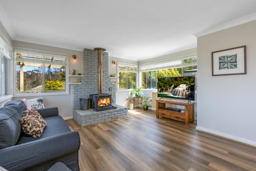 Una sala de estar con un sofá y una chimenea. en Sunflower Cottage, en Katoomba
