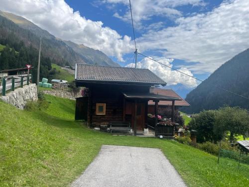 a cabin in the mountains with a gravel road in front at Mühle in Görtschach in Sankt Veit in Defereggen