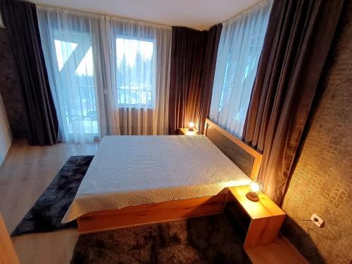 ein Schlafzimmer mit einem Bett und einem großen Fenster in der Unterkunft Viva 4 Apartment ski to the door complex Grand Monastery Pamporovo in Pamporowo