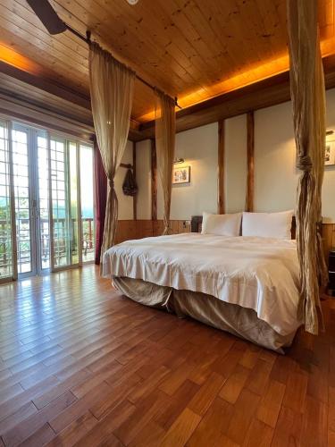 a bedroom with a large bed in a room with wooden floors at Cingjing Vienna Pleasance Cottage in Ren'ai