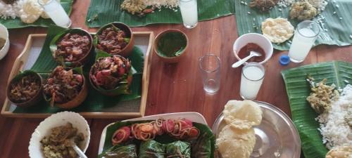 a wooden table with plates of food on it at Mundro Garden Homestay in Munroe Island