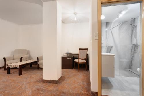 a bathroom with a shower and a table and a chair at Hotel Pegaz in Krynica Zdrój
