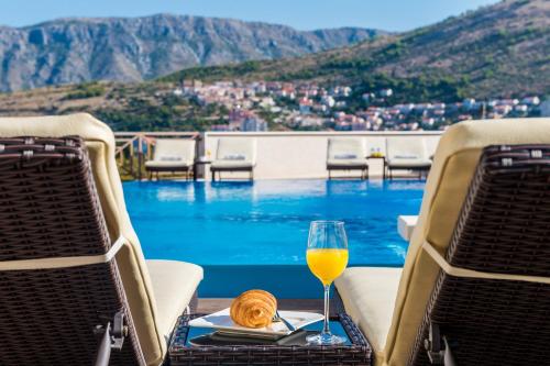 una copa de vino sentada en una mesa junto a una piscina en Villa Peragro, en Dubrovnik