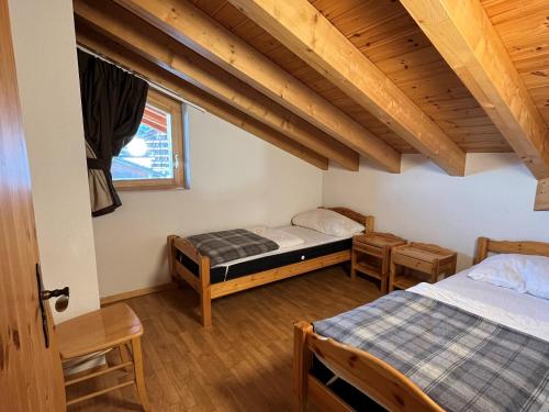 a bedroom with two beds and wooden ceilings at Pracondu 2 504 - OUTDOOR & FUN charming apartment 8 personnes in Nendaz
