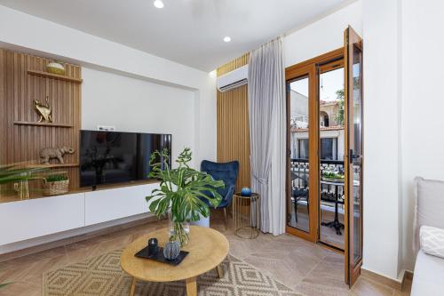Una sala de estar con un televisor, un sofá y una mesa. en Queen Stella Luxury Homes - Adults Only!, en Rethymno