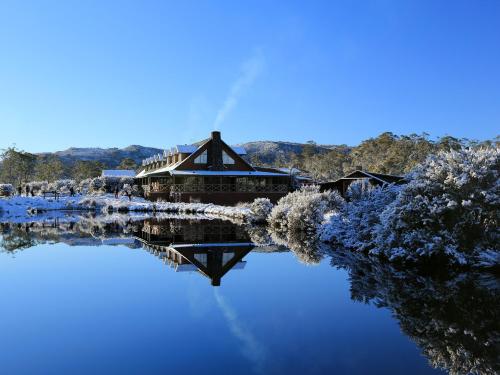 a building sitting on top of a lake in the snow at Peppers Cradle Mountain Lodge in Cradle Mountain