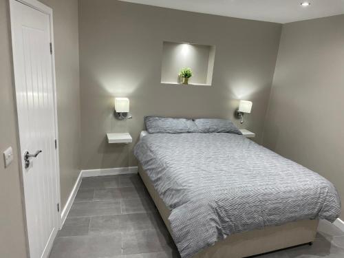 One bedroom apartment في Goodmayes: غرفة نوم بسرير واضاءين على الحائط