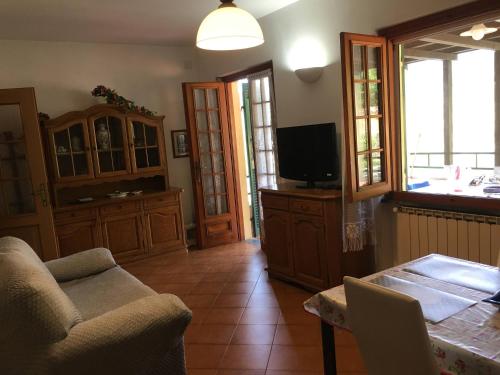 ein Wohnzimmer mit einem TV, einem Sofa und einem Tisch in der Unterkunft Le Ginestre in Levanto