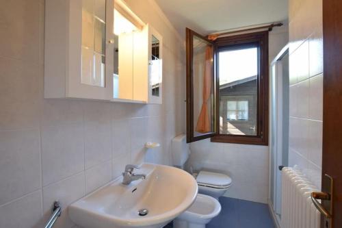 a bathroom with a sink and a toilet and a window at VILLA MAGNOLIA vicino al mare in Isola Albarella