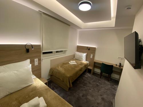 a room with two beds and a desk and a television at Konak Stella in Belgrade