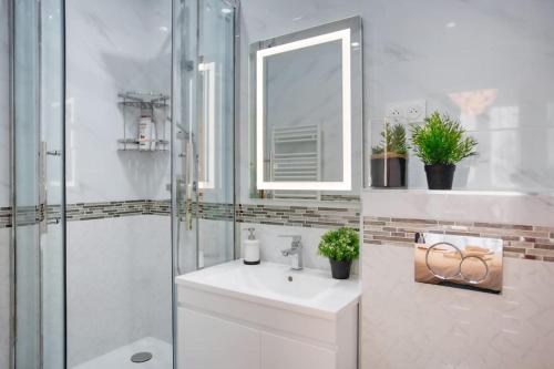 une salle de bain blanche avec un lavabo et un miroir dans l'établissement Chaleureux 100m2 3CH - Séjour Romantique Parfait, à Paris
