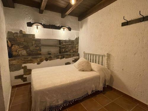 - une chambre avec un lit dans une pièce dotée d'un mur en pierre dans l'établissement Casa Rural El Chacho - Velefique, à Velefique