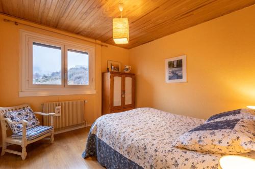 a bedroom with a bed and a chair and a window at Carols in Font-Romeu-Odeillo-Via