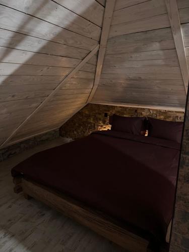 a bed in a attic with a wooden ceiling at Luxury Live in Kamianets-Podilskyi