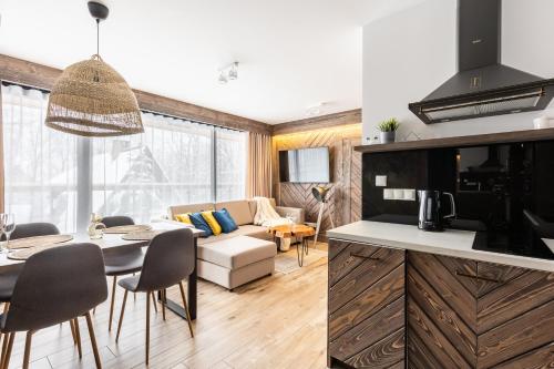 a kitchen and living room with a table and a couch at Apartamenty Małe Żywczańskie Lux&SPA in Zakopane