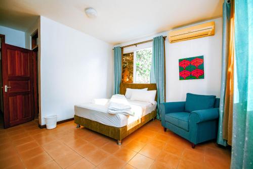 um quarto com uma cama e uma cadeira azul em Dafina Residence em Dar es Salaam