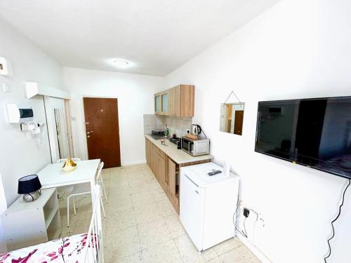 a small kitchen with a table and a tv at Central Comfort Studio in Larnaca
