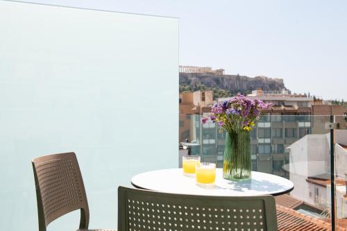 a table with two glasses of orange juice and a vase of flowers at Enattica Suites in Athens